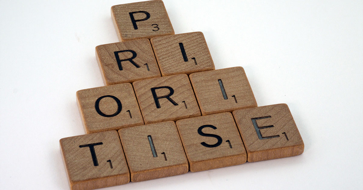 Scrabble tiles on a white table that spell out the word 'priorities'